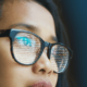 Frau blickt nach vorne mit digitalen Coderekflektionen in den Brillengläsern